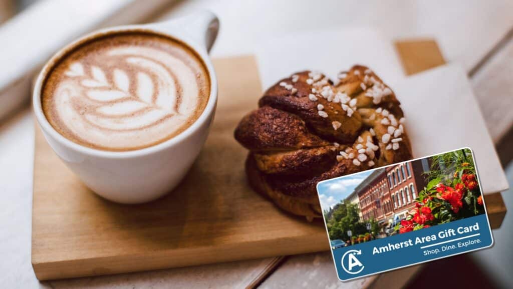 A cup of coffee and a pastry on a wooden board. Treat yourself in downtown Amherst.