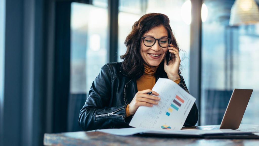 Entrepreneur smiling looking at the statistics while in a phone call