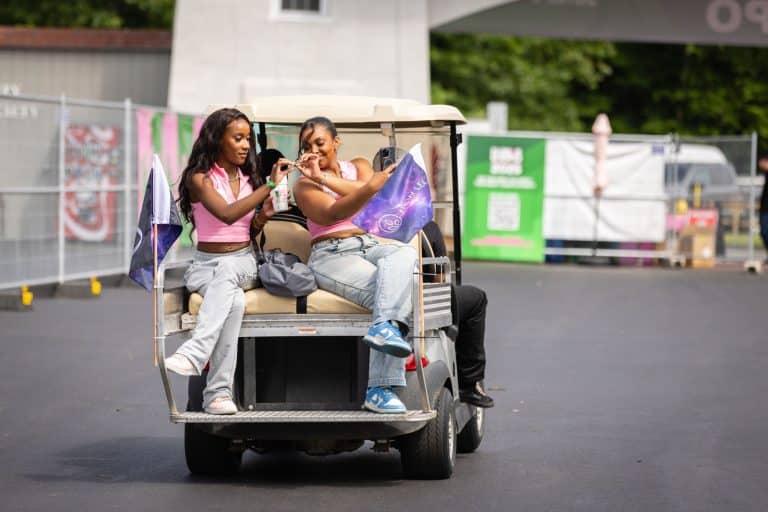 Sharing is caring. Two women share some product on a golf cart at Flower Expo.