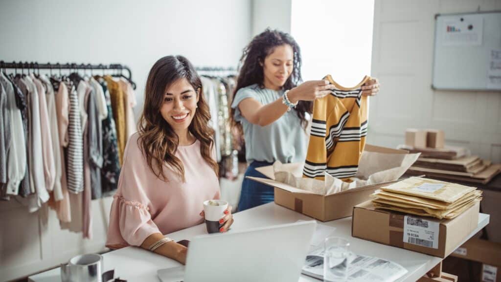 Two business owners in their clothing shop packing orders to ship.