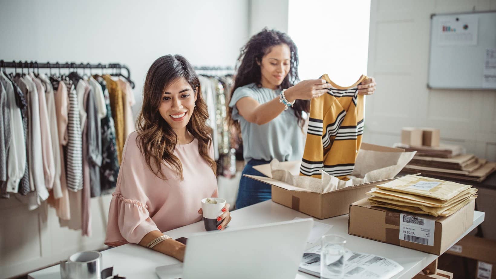 Two business owners in their clothing shop packing orders to ship.