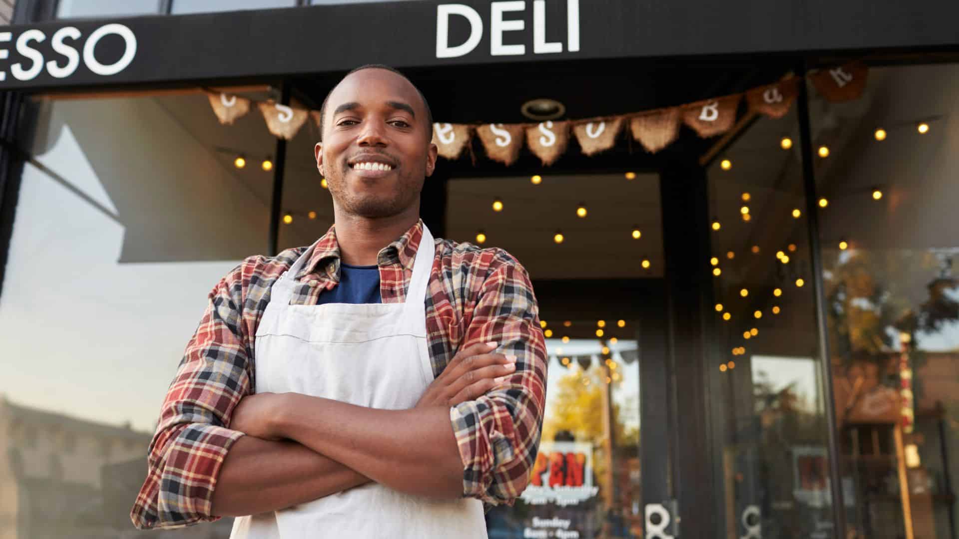 Business owner proudly smiling in front of his newly opened coffee shop.