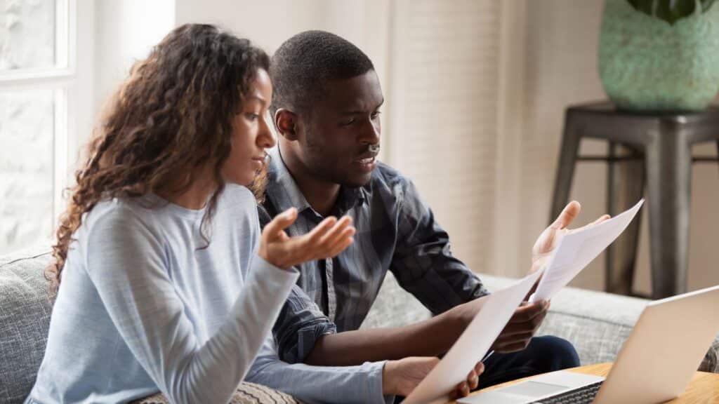 Business owners sitting on couch with laptop on coffee table trying to understand paperwork for BOI reporting guidelines