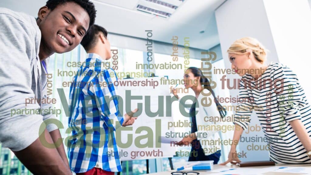 Image showing team standing around a whiteboard with words depicting investments overlaid over the image
