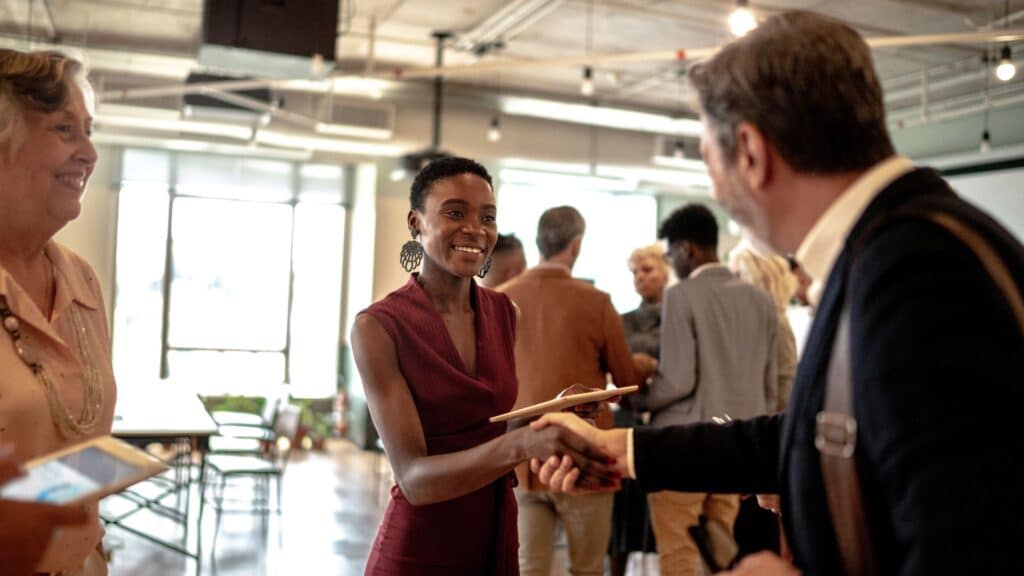 A host welcomes a guest to a networking event.