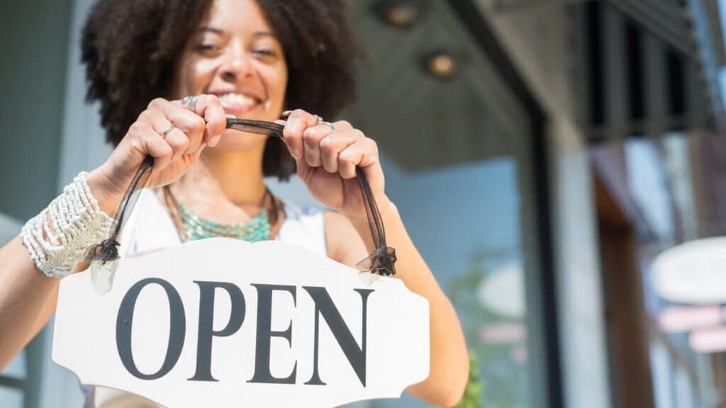 Business woman putting her open sign in her shop.