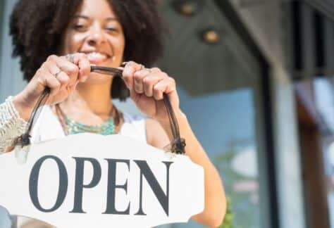 Business woman putting her open sign in her shop.
