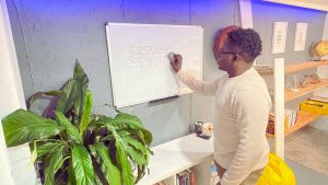 Owwtreach Founder & CEO, Fungai Tichawangana, erases the name 'Artist Dynamix' off a whiteboard.